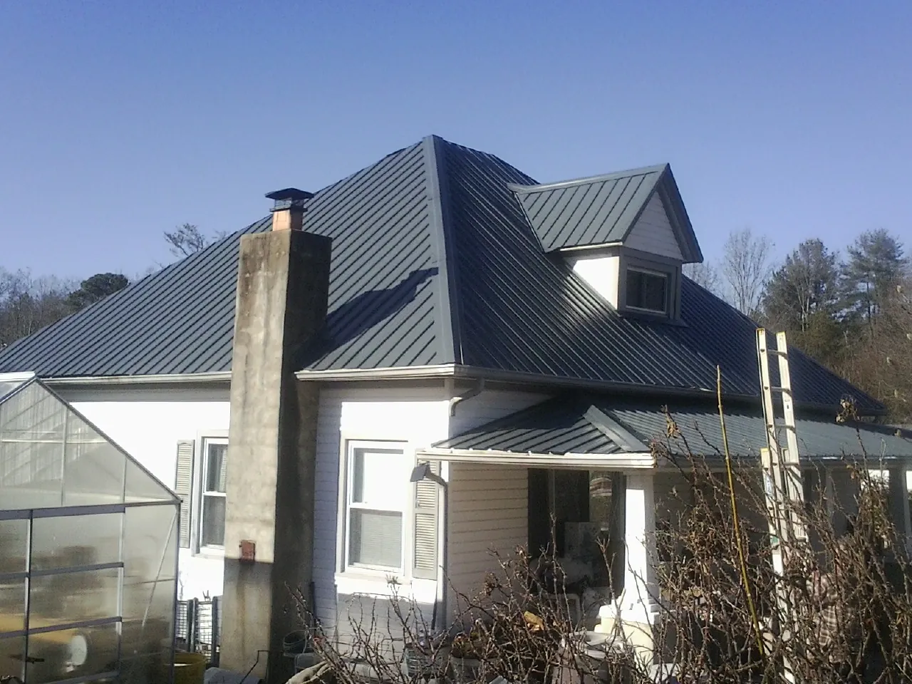 Dark blue standing seam metal roof on a white farmhouse with dormer — Slate & Tile Roof Repair by Roofing Brothers in Winterthur