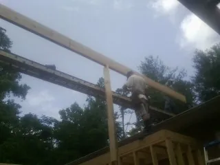 Carpenter setting a ridge beam over a new addition frame — Ice Dam Removal by Roofing Brothers in Winterthur