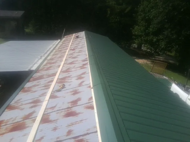 Old rusted panels beside newly installed green metal roofing — Wind Damage Roof Repair by Roofing Brothers in Winterthur