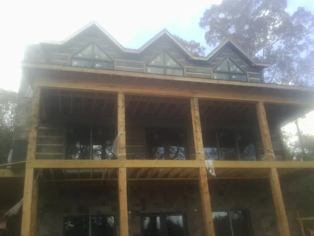 Dormers and porch framing on a large log home under construction — Roof Coating work by our crew in Winterthur