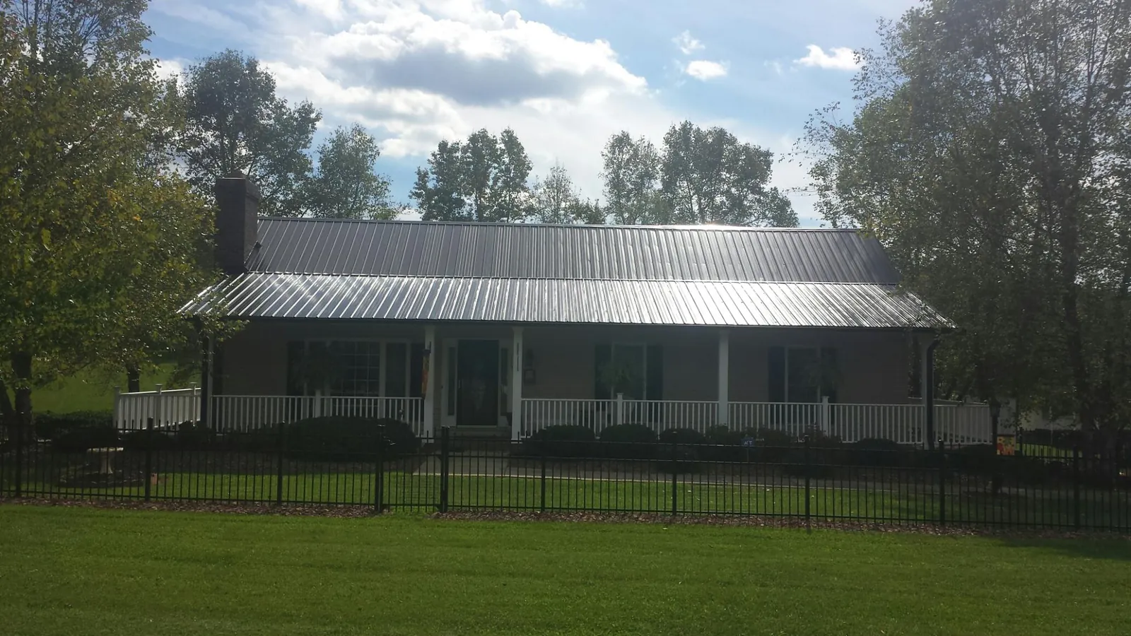 Gray metal roof on a brick ranch with a full width front porch — Gutter Guard Installation work by our crew in Winterthur