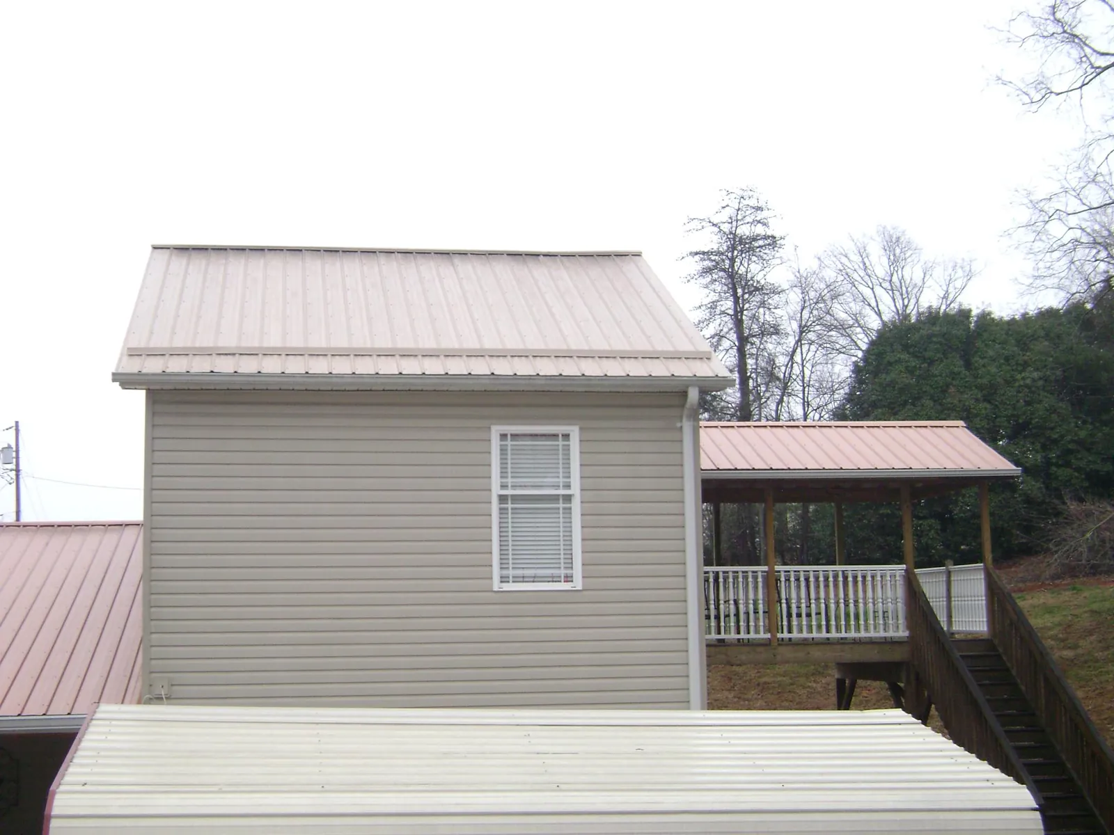 Tan metal roofs on a two story addition and attached porch, from a Roof Replacement job in Winterthur