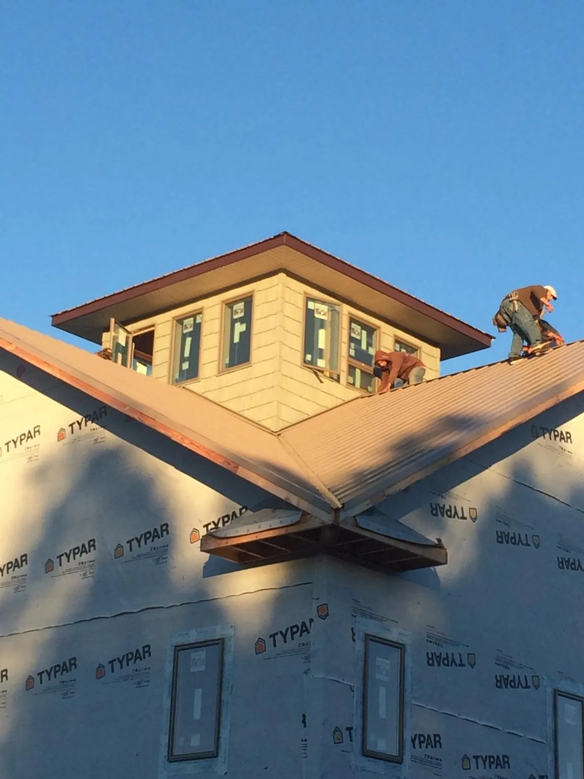 Roofers working around a rooftop cupola on a new metal roof at sunset — Roof Waterproofing in Winterthur by Roofing Brothers